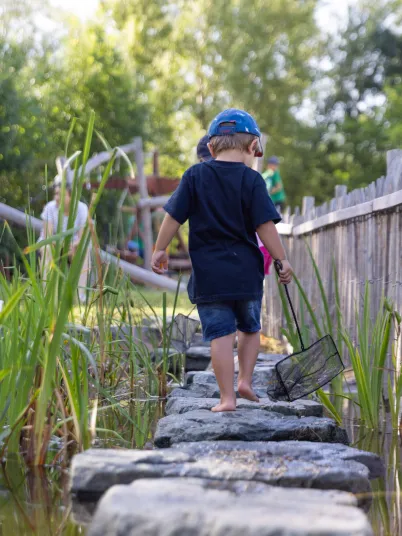 Kleiner Junge geht barfuß über Steine