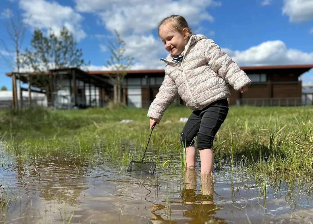 Kleines Mädchen keschert in Wasserpfütze